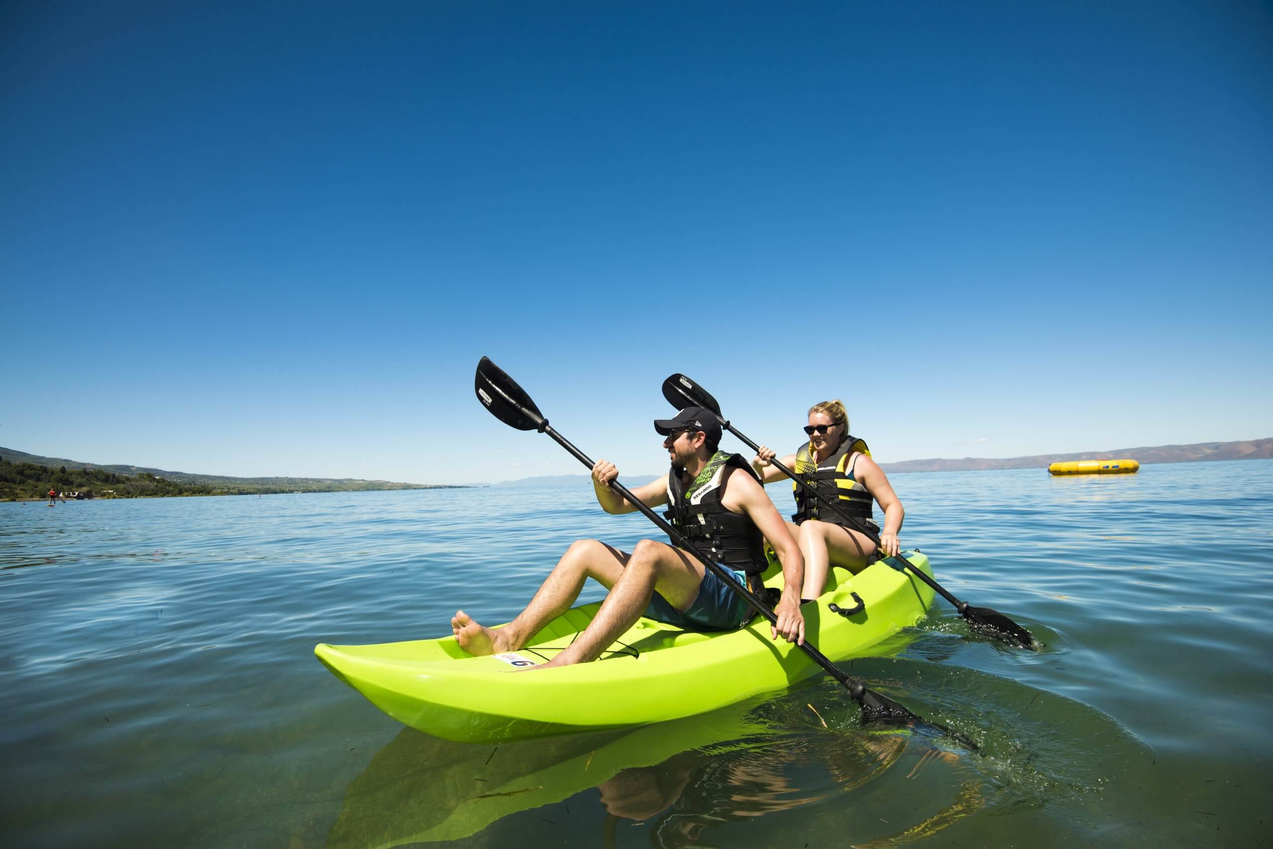 Two people paddling in a green kayak at Bear Lake.