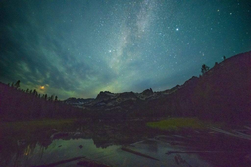 A dark turquoise night sky filled with stars stretches out over the Sawtooth Mountains.