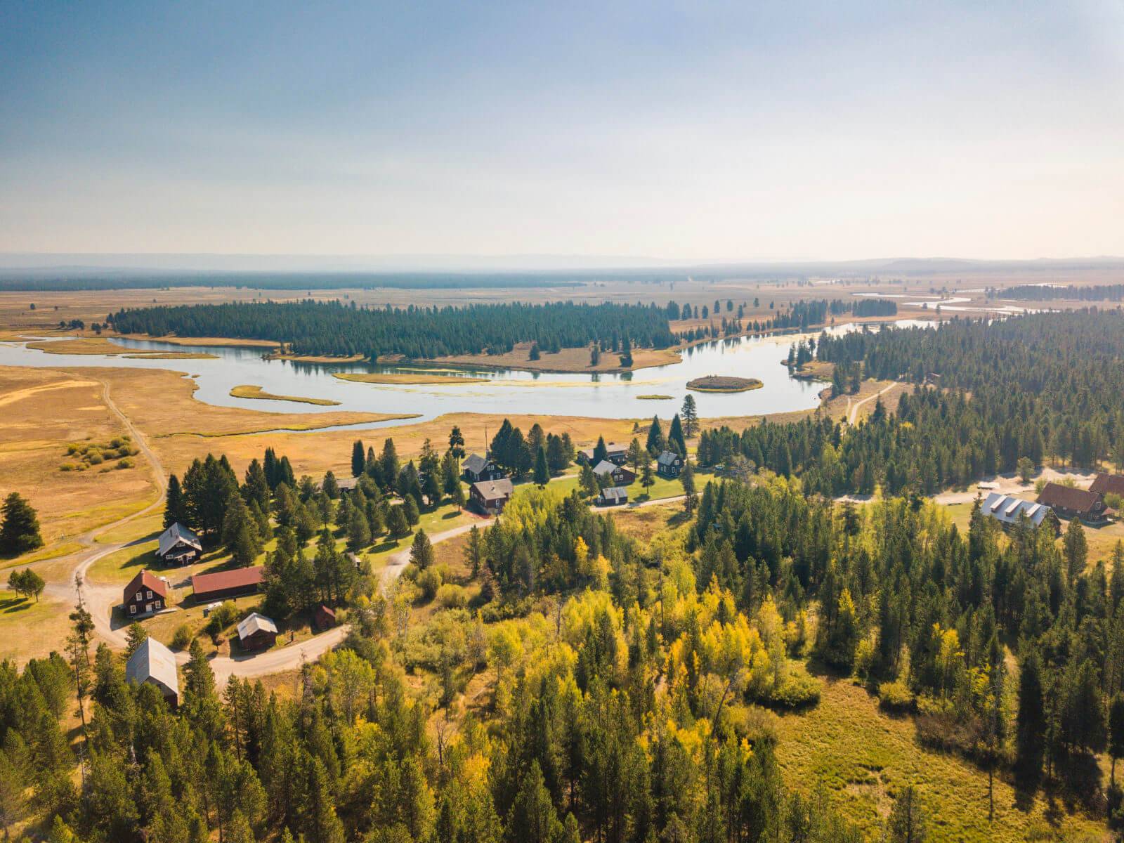 An aerial view of a state park made up of buildings, forest and river during fall.