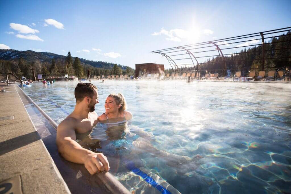 A couple smiles in an outdoor developed hot springs pool.