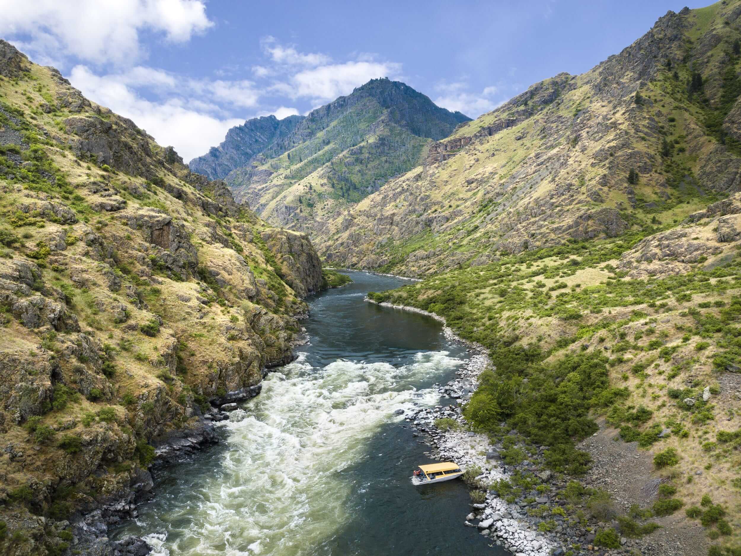 An aerial view of a yellow jet boat on the bank of the Snake River in Hells Canyon.