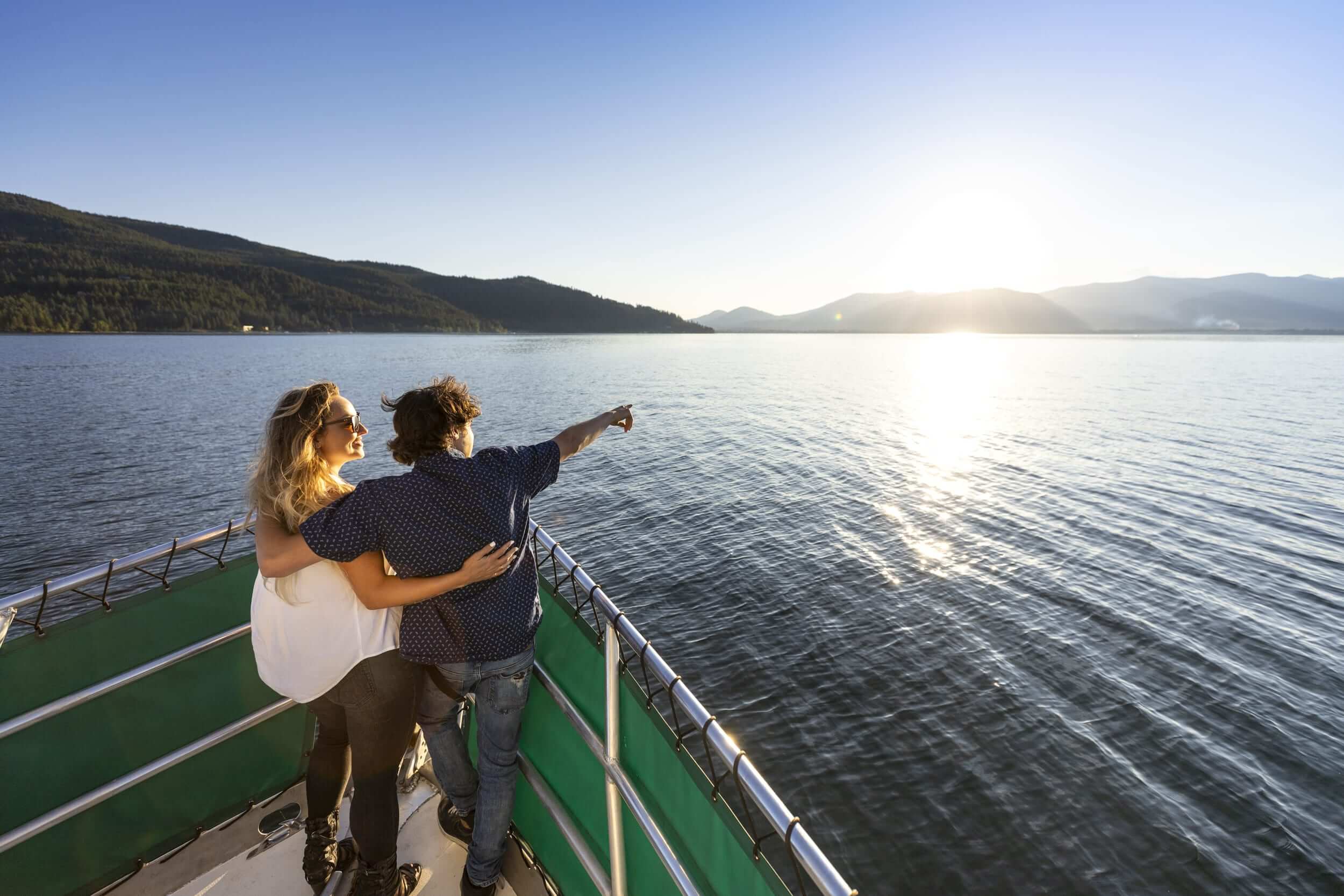 Two people on a boat pointing at Lake Pend Oreille.