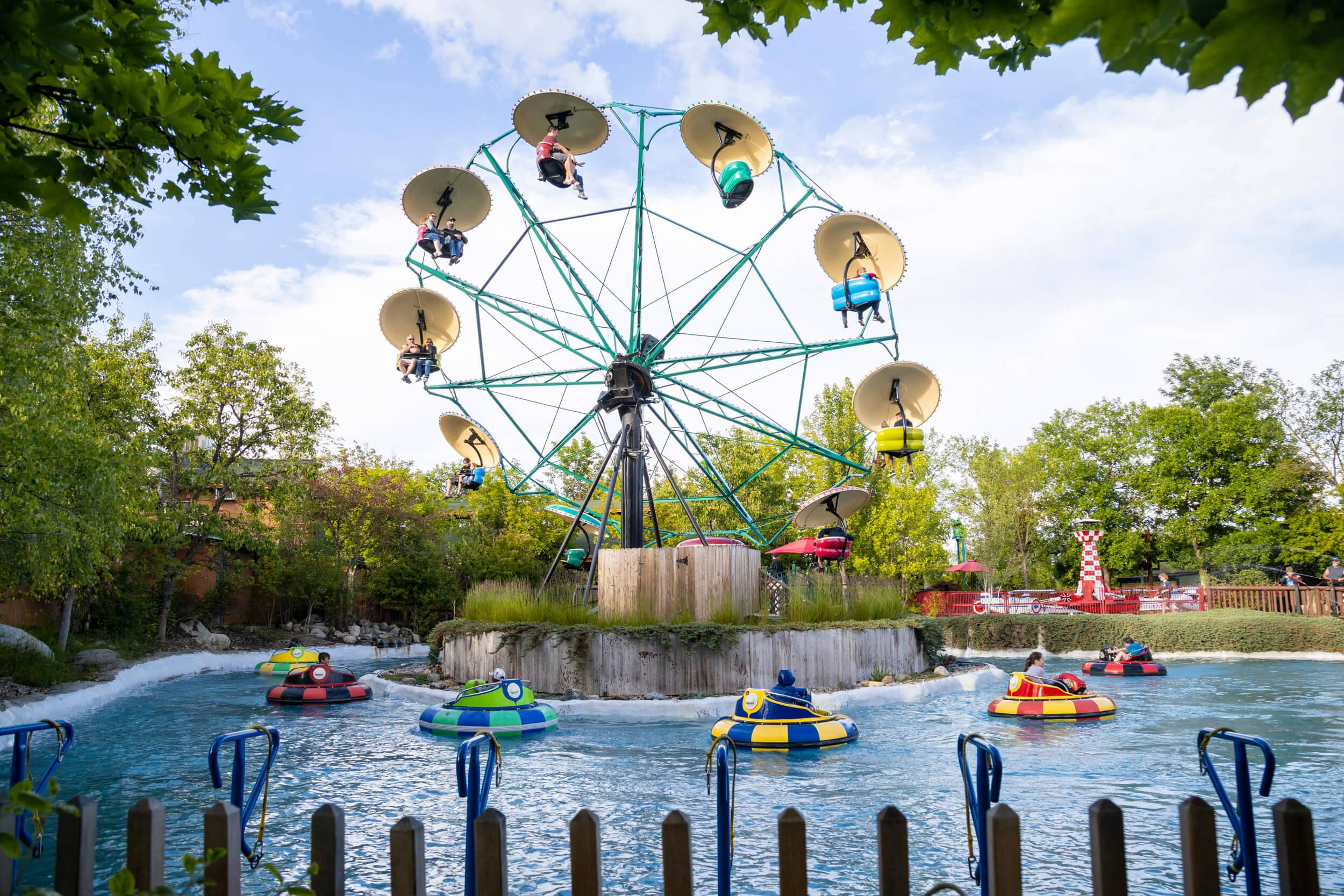 People in bumper boats float around a ferris wheel at Silverwood Theme Park.