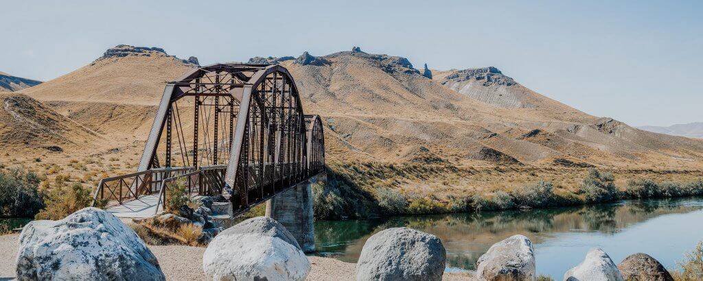 view of an bridge going across a river with mountains in the background