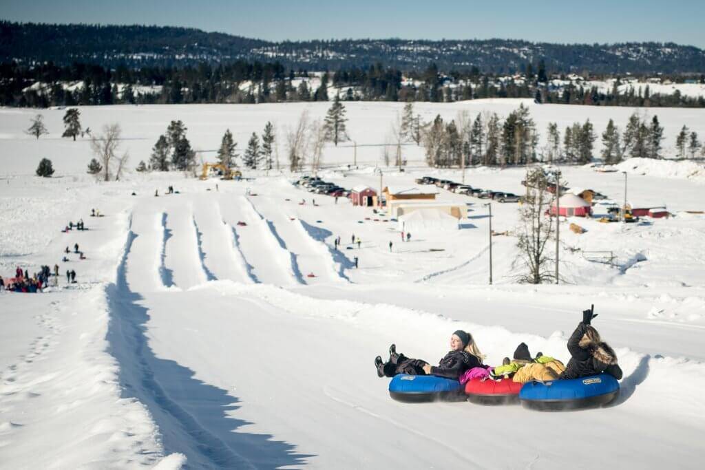 people snow tubing down hill with designated lanes at the McCall Activity Barn.