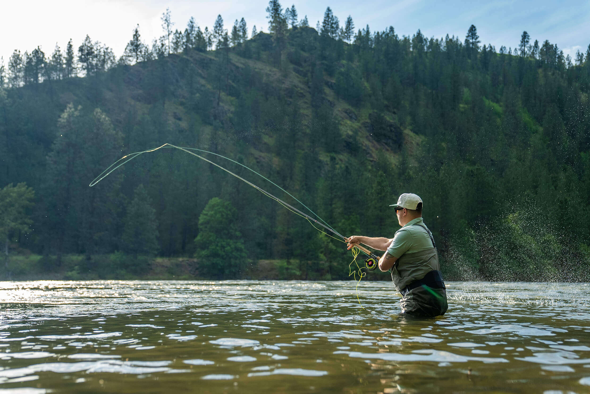 A man dressed in waders casts a line into the Clearwater River.