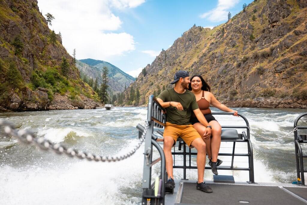 A man and woman smile as they ride a jet boat through the Salmon River.
