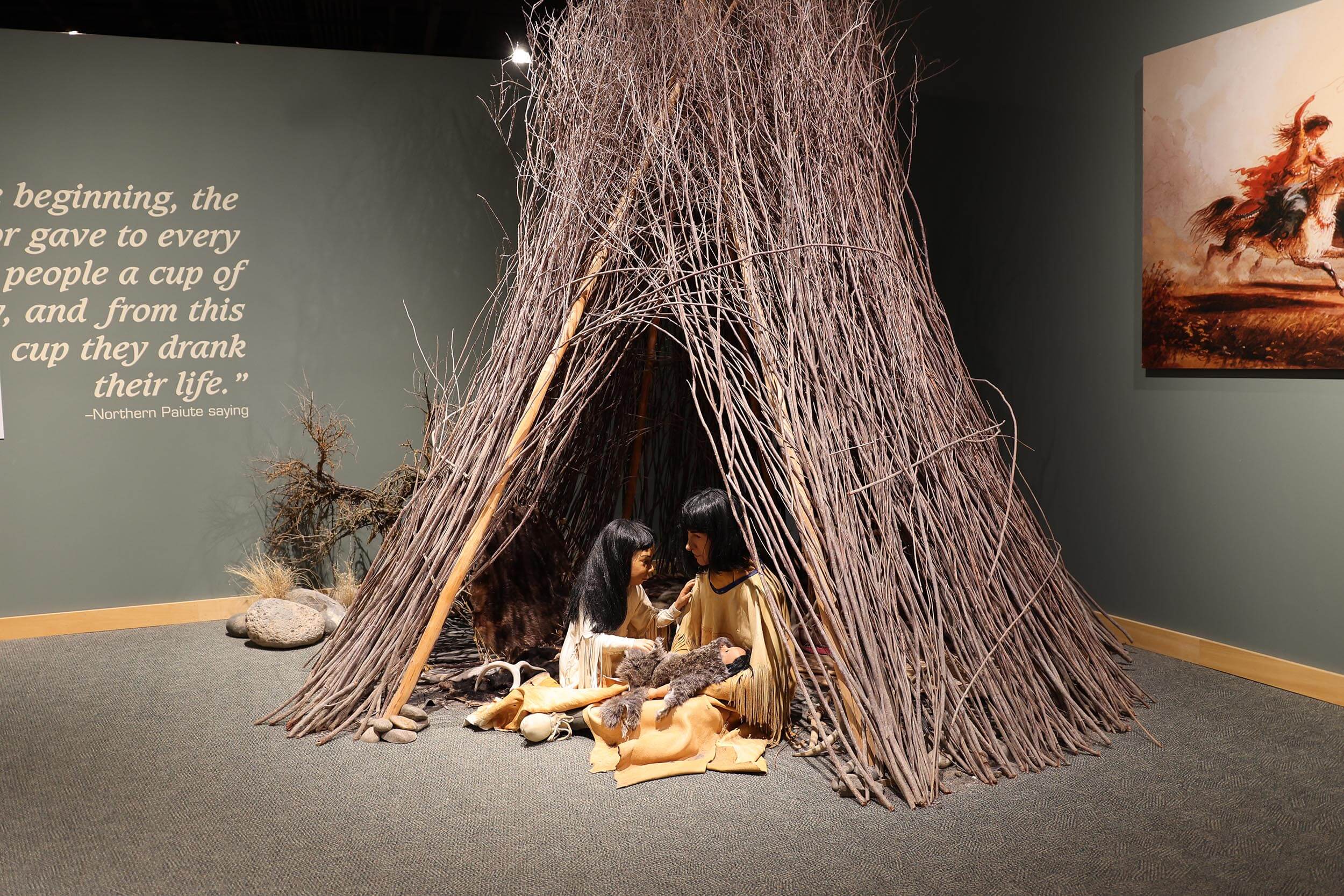 a museum exhibit and replica of Native Americans sitting inside a teepee