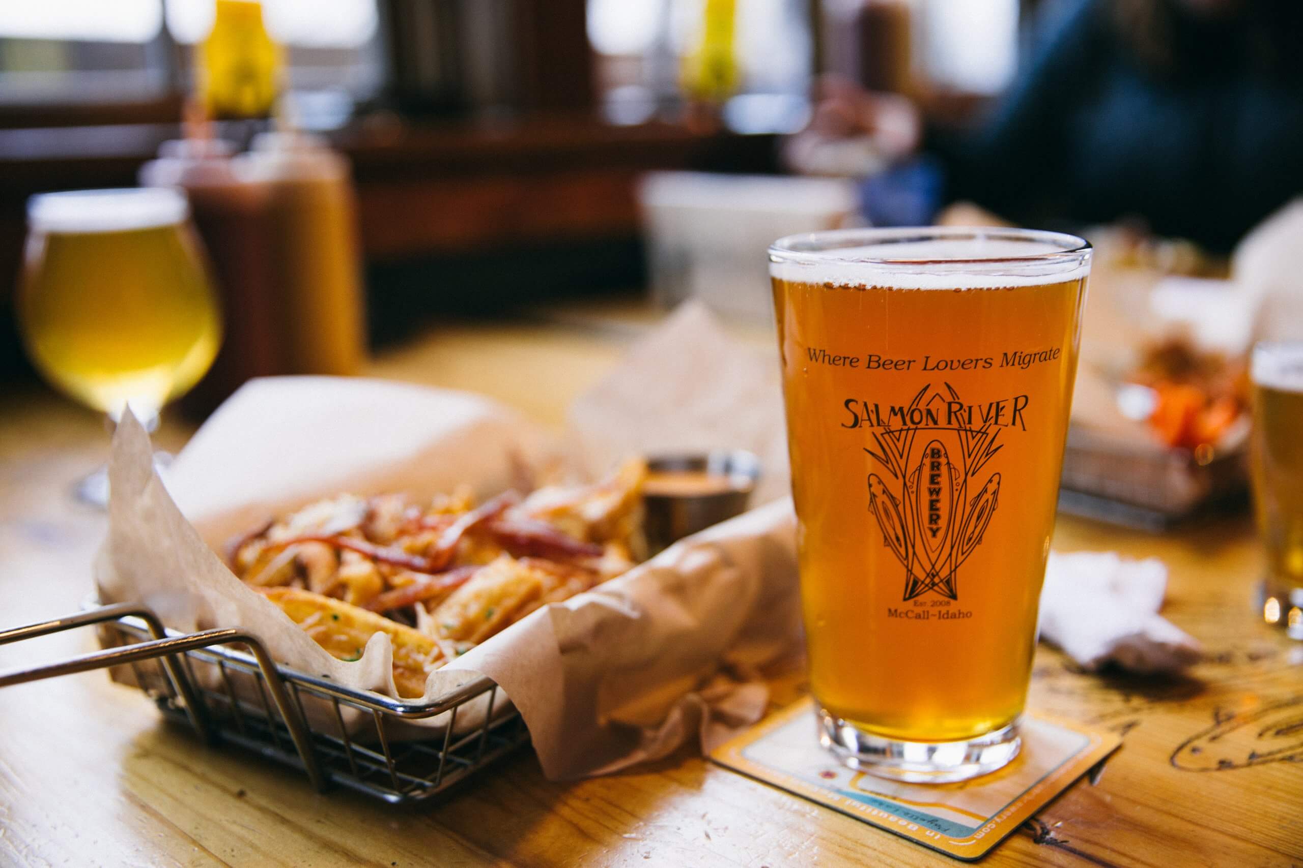 A closeup view of a glass of beer and basket of fries on a table at Salmon River Brewery.