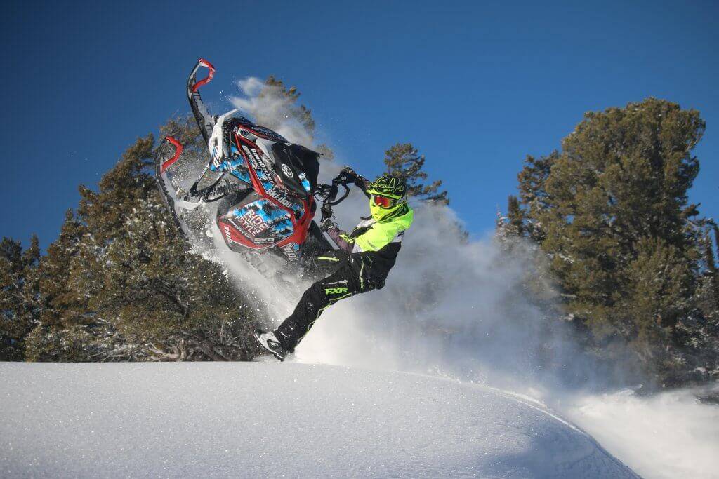 A snowmobiler launches off a jump on a winter trail in Bear Lake Valley.