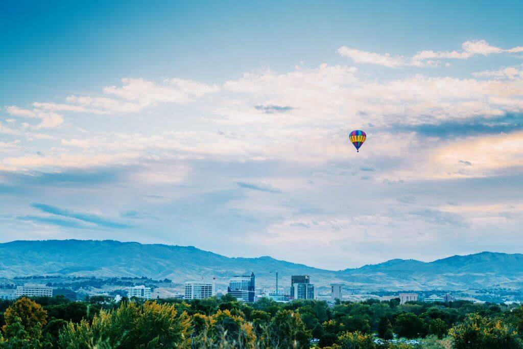 An air balloon floating over a city landscape.