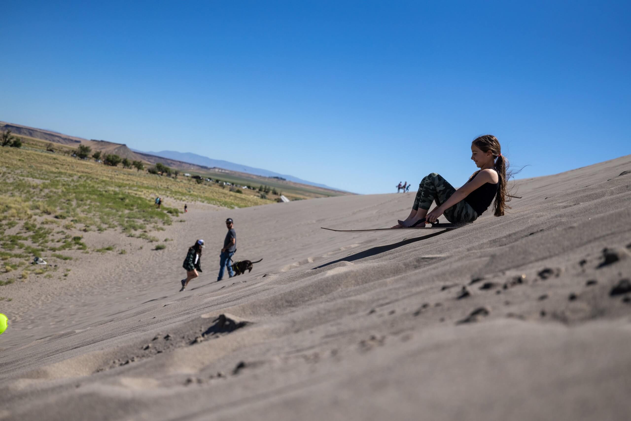A girl slides down a sand dune on a board at Bruneau Dunes State Park.