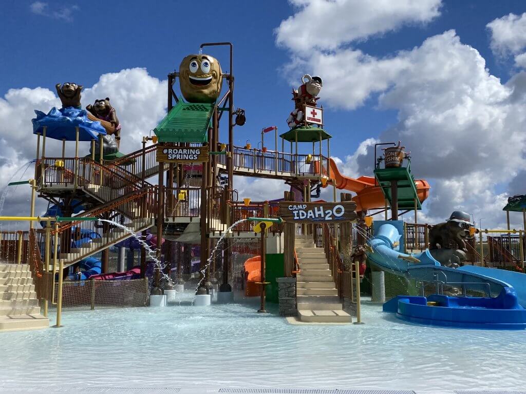 A water feature play area with waterslides and a giant potato-shaped tipping water bucket.