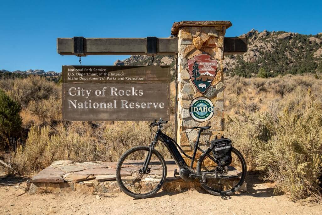 black bike standing in front of city of rocks national reserve sign with sagebrush in background