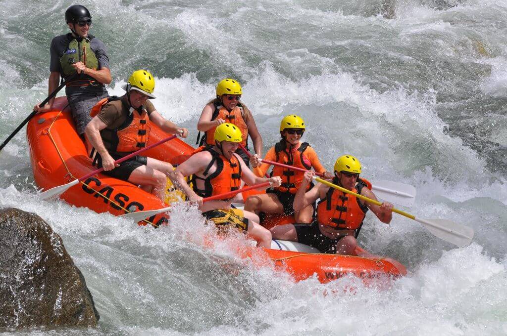 6 people on orange water raft with large waves