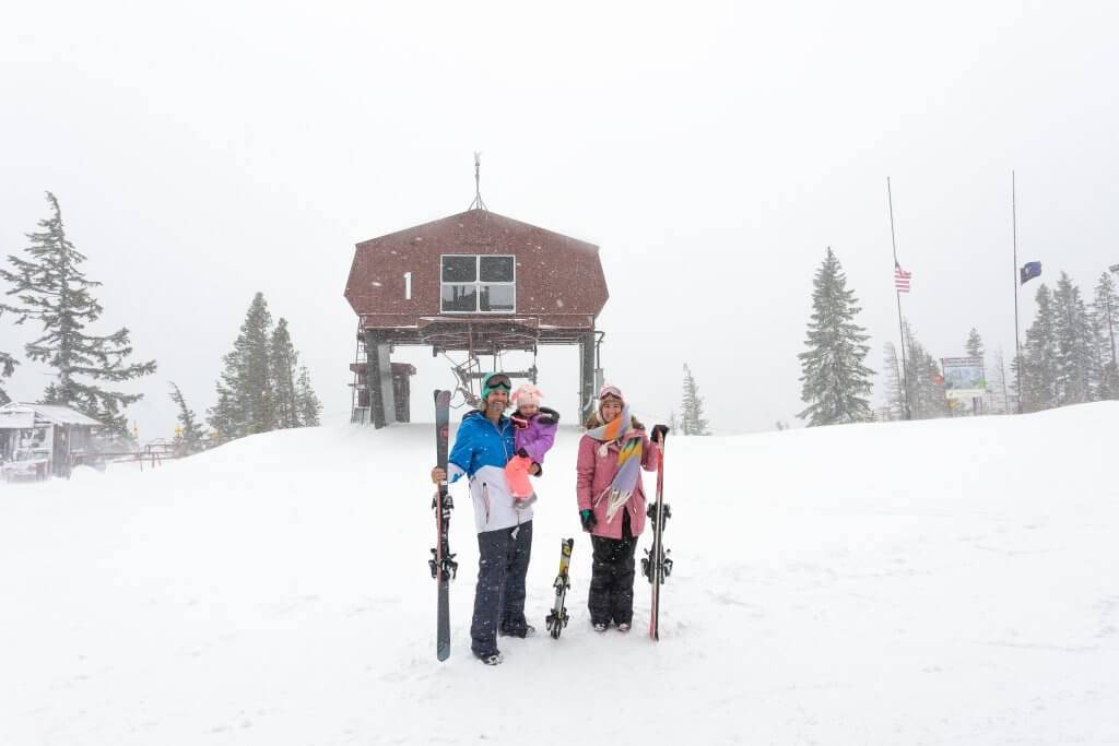 family at top of ski hill with skis