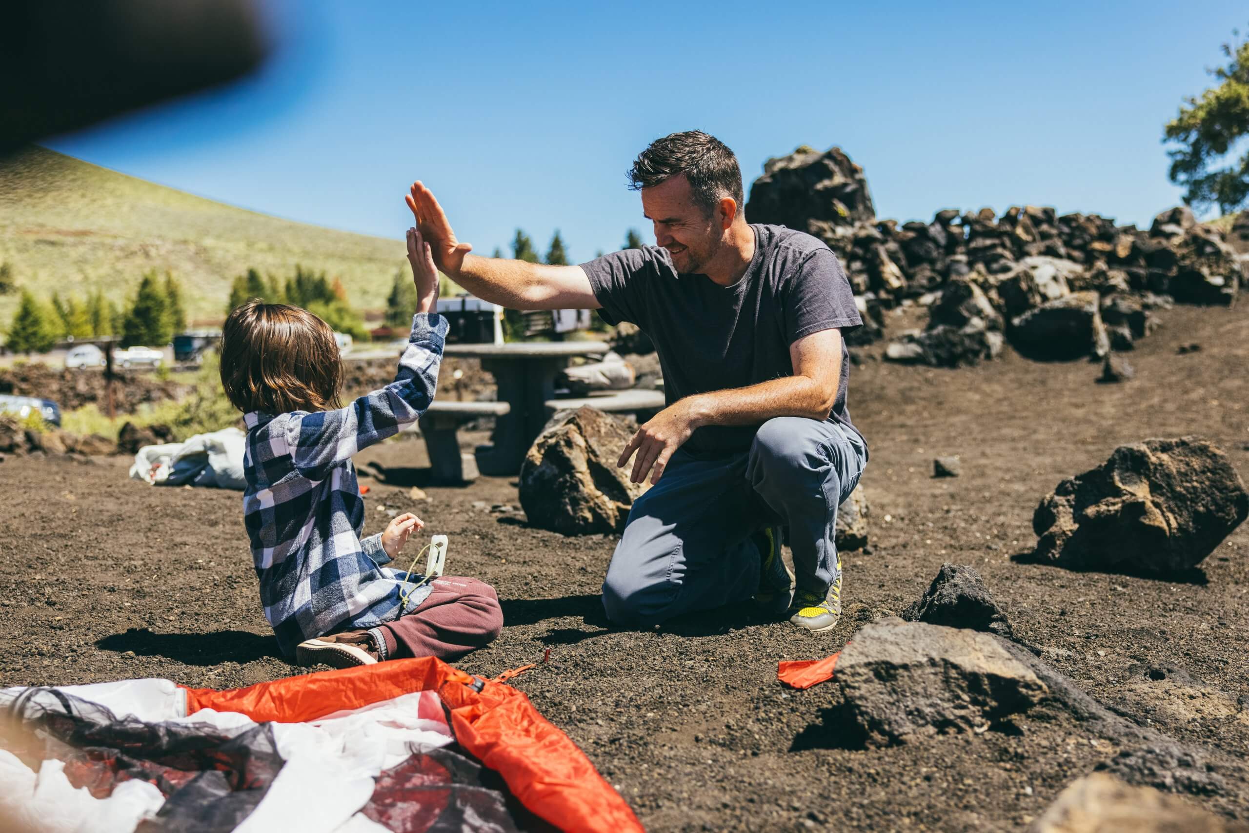 A father and child high five in the Lava Flow Campground