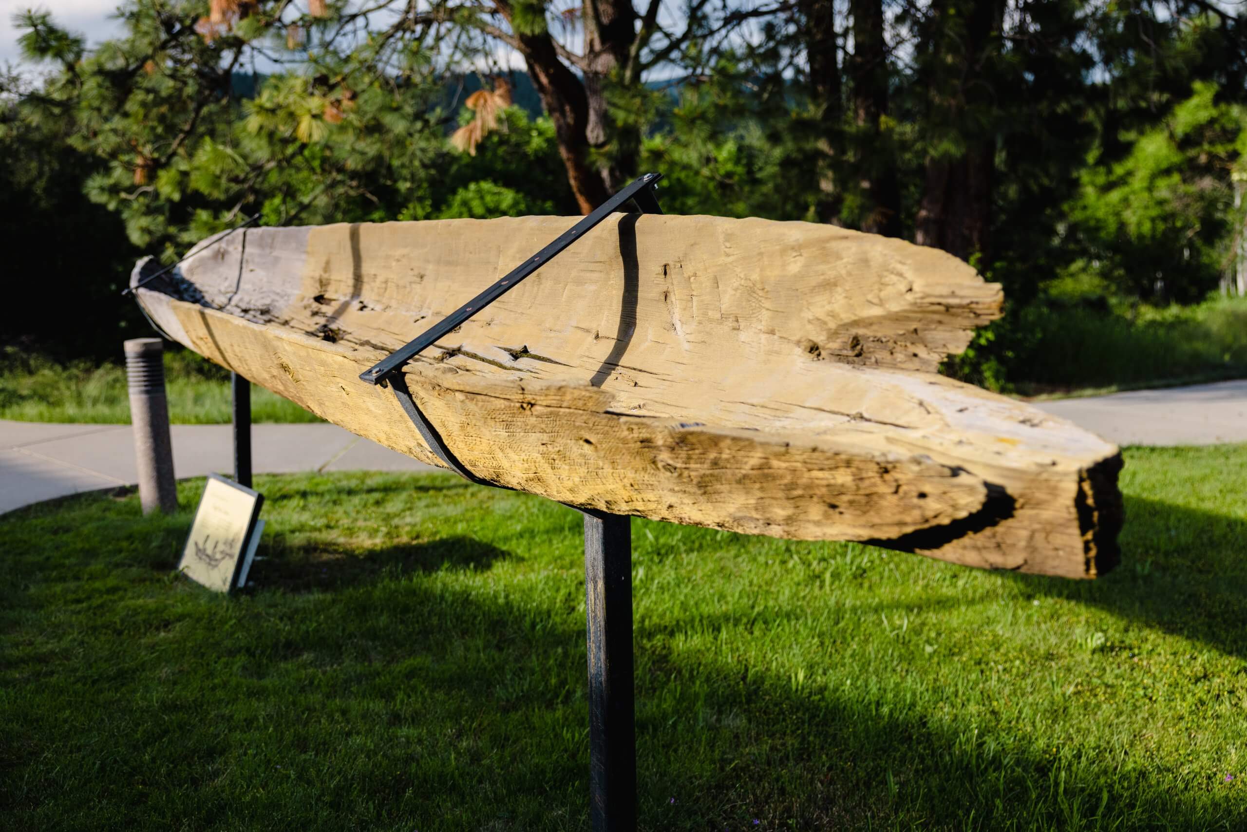 A carved canoe displayed in a grassy area.