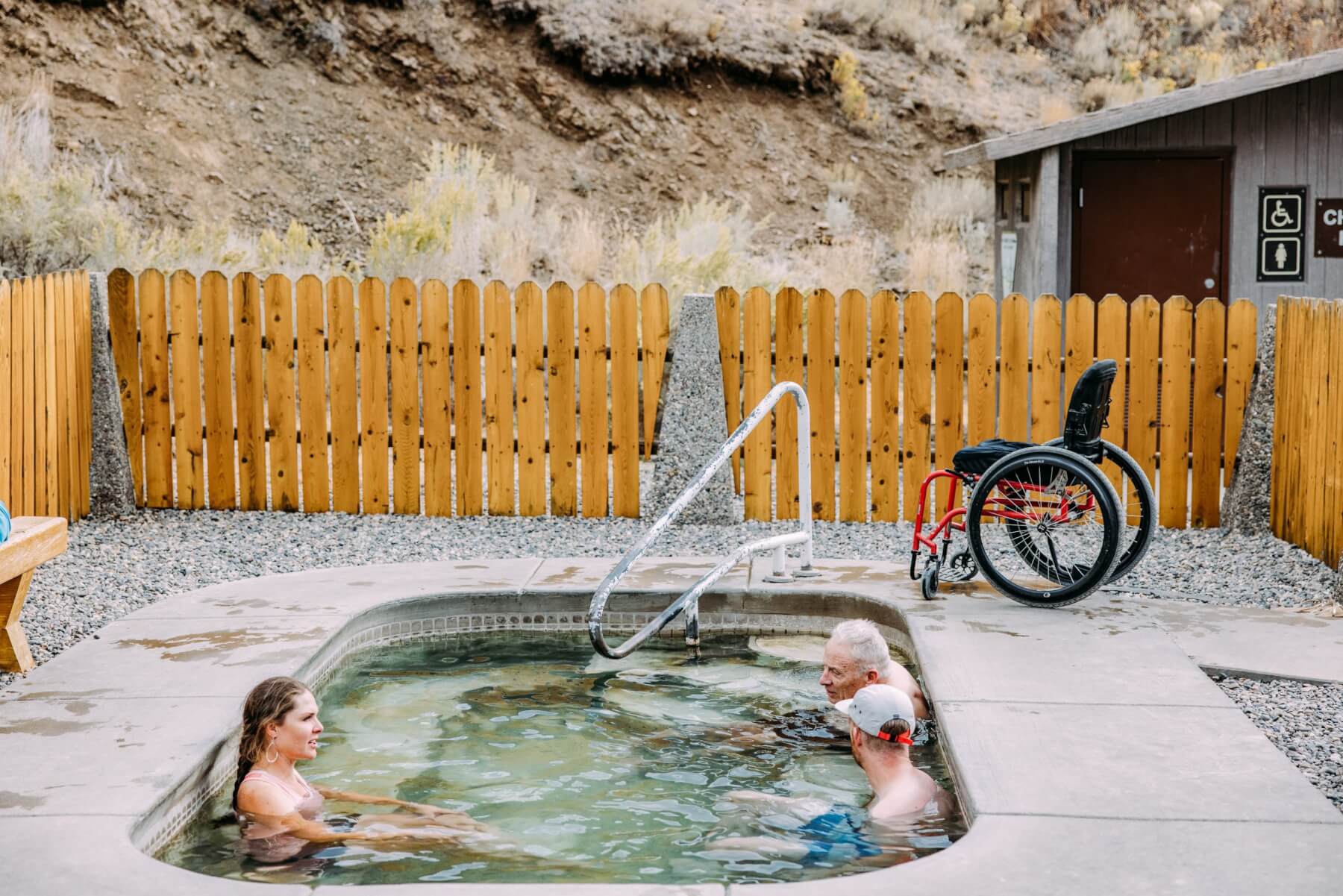 Three people relax in a hot springs pool