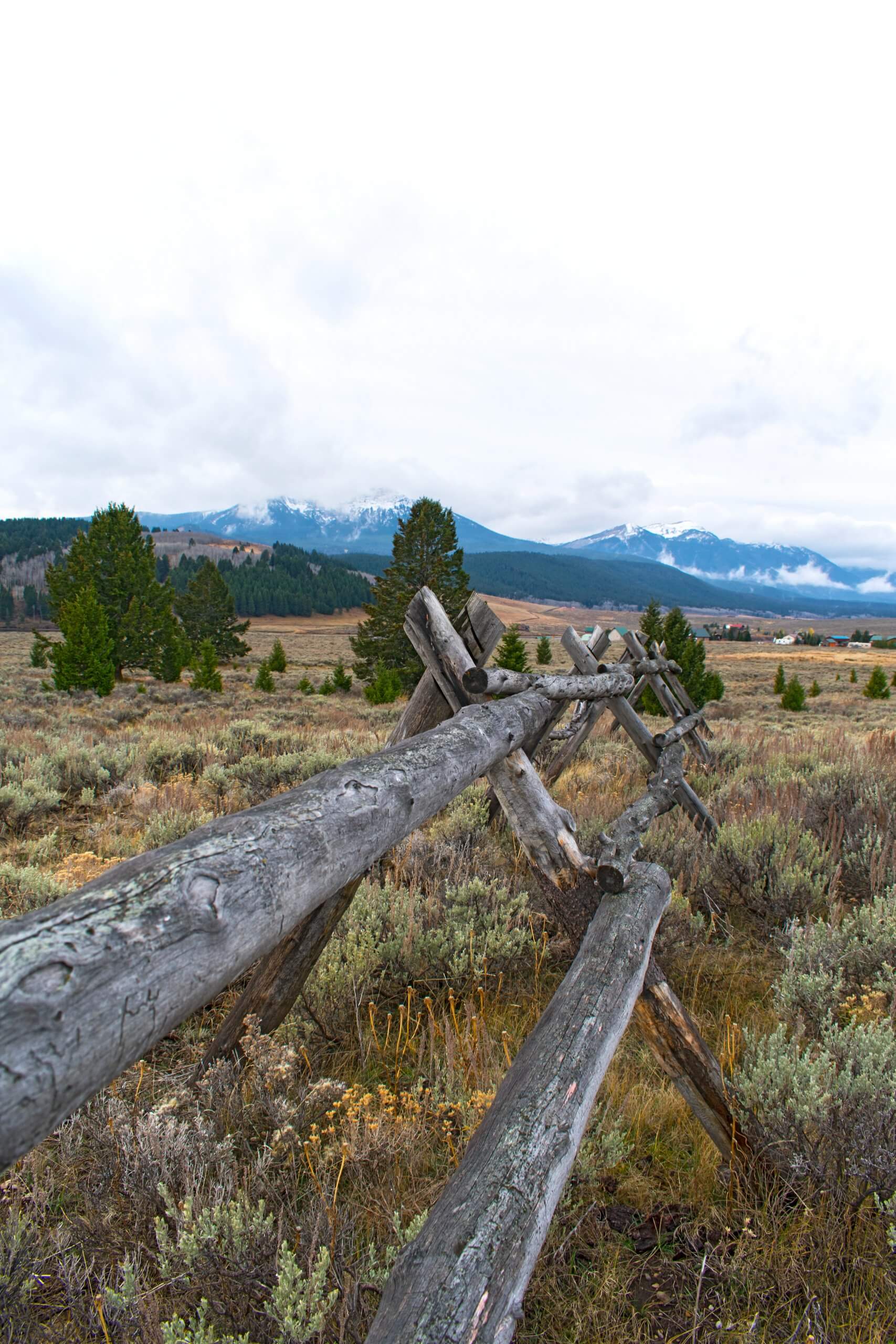 Wooden fence at Henrys Lake State Park with snow-capped mountains in the distance.