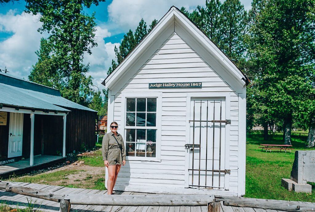A woman stands outside a white historic building in Idaho City.