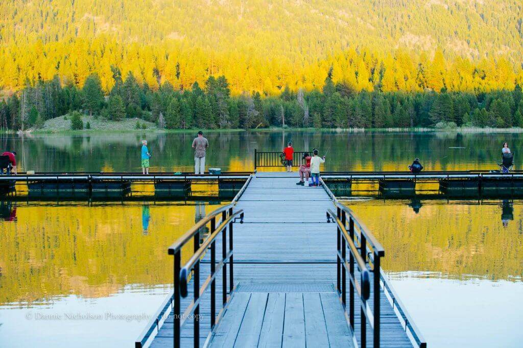 People standing at the end of a dock, fishing in the Horsethief Reservoir.