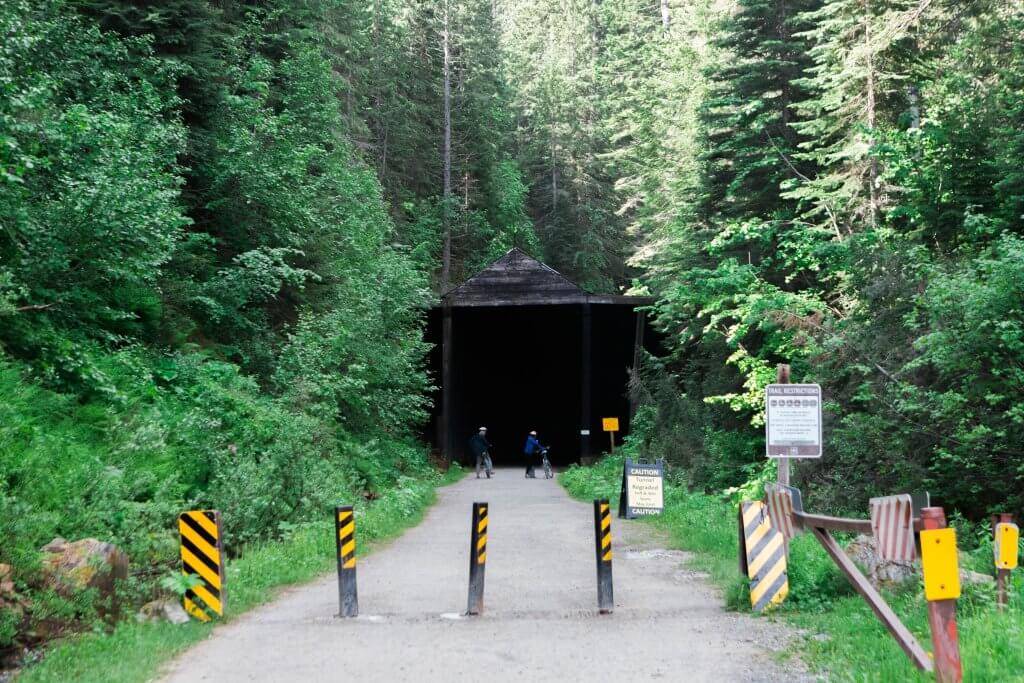 two bike riders standing with bikes in front of tunnel entrance on the Route of the Hiawatha trail