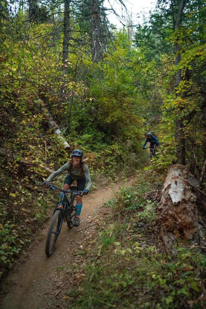 A person on a mountain bike rides a dirt trail that cuts through heavy foliage on Canfield Mountain.