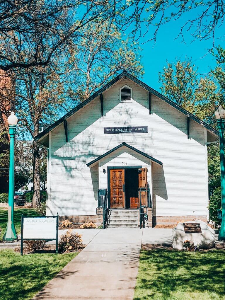 Exterior image of the Idaho Black History Museum housed in a small church-like building that is white with black trim in Julia Davis Park. 
