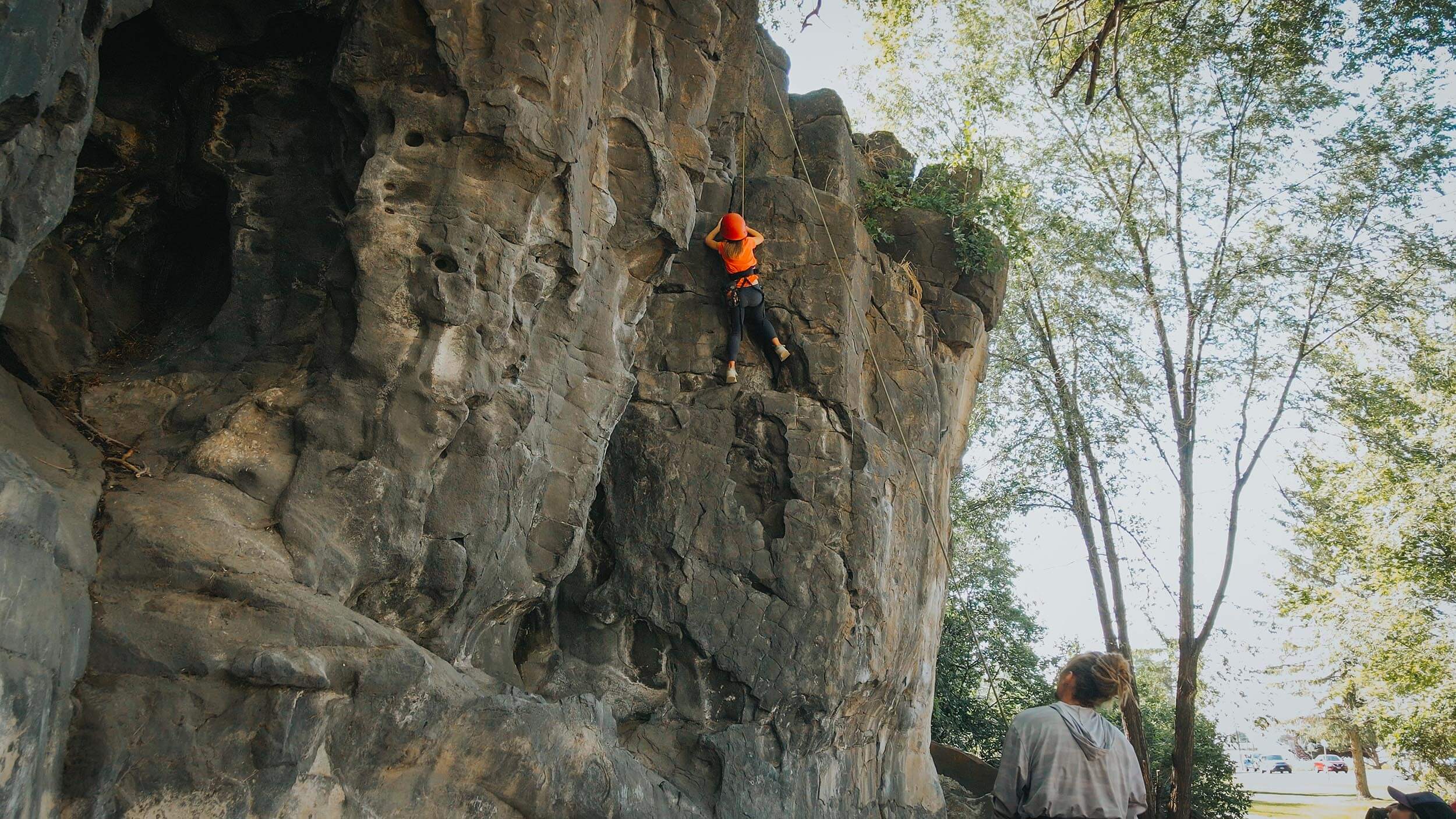 a child in orange rock climbs on a rock formation