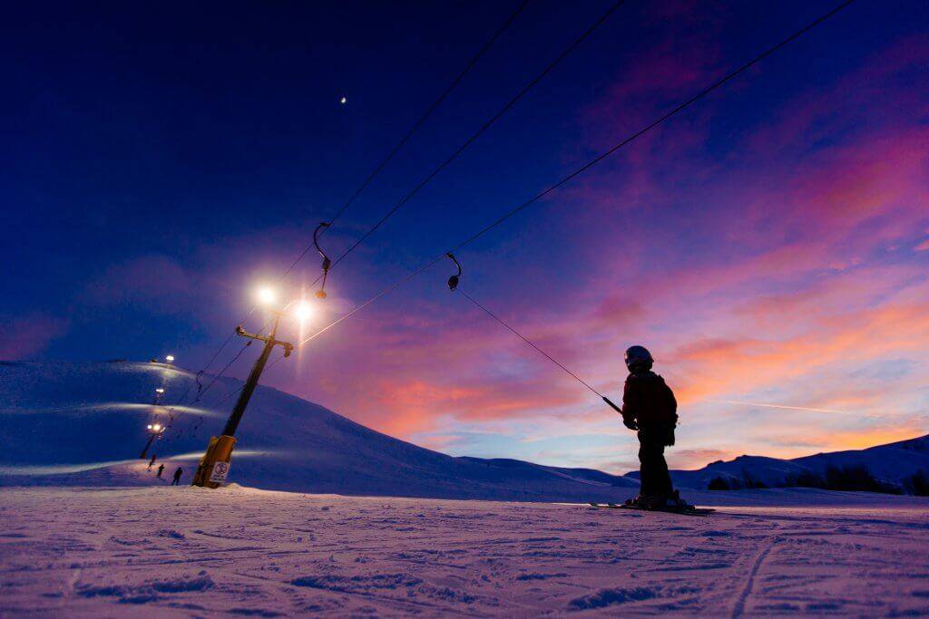 A child on ski pull line during a colorful sunset at Rotarun Ski Area.
