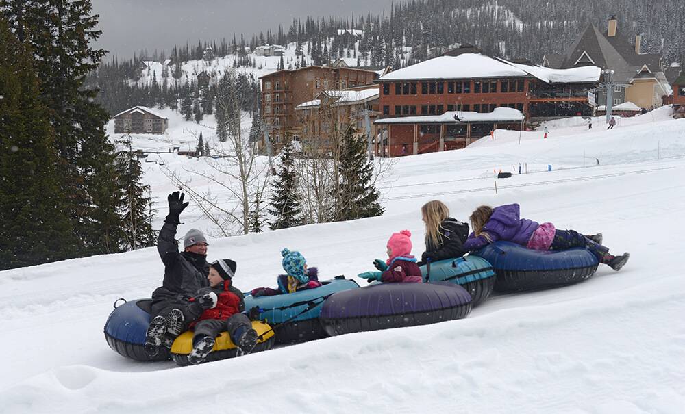 Family tubing down a hill in winter