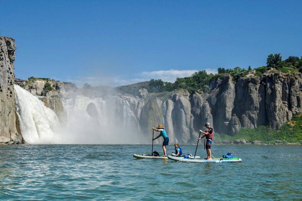 paddleboarders by waterfall