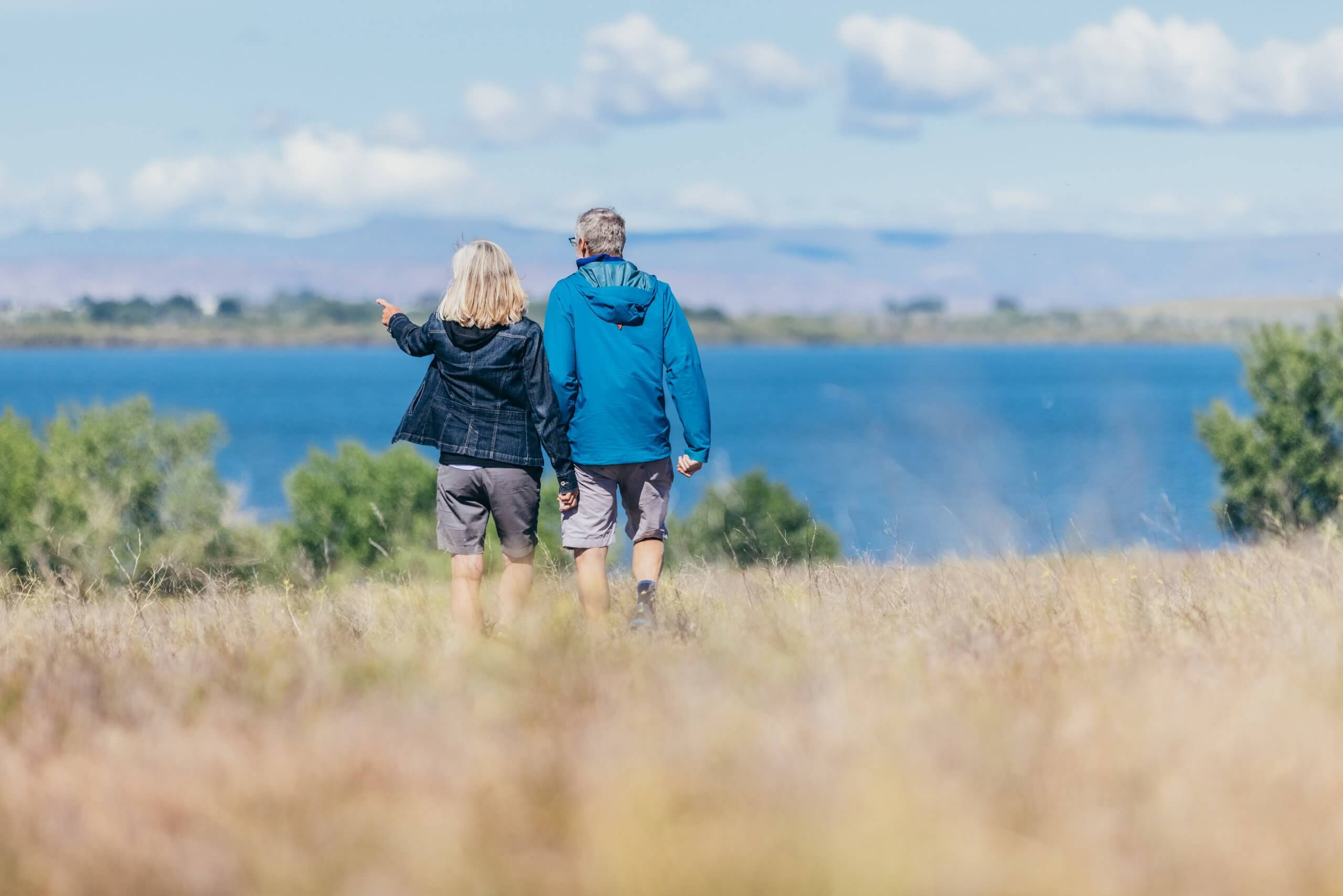 back view of two people at a wildlife refuge walking towards a lake