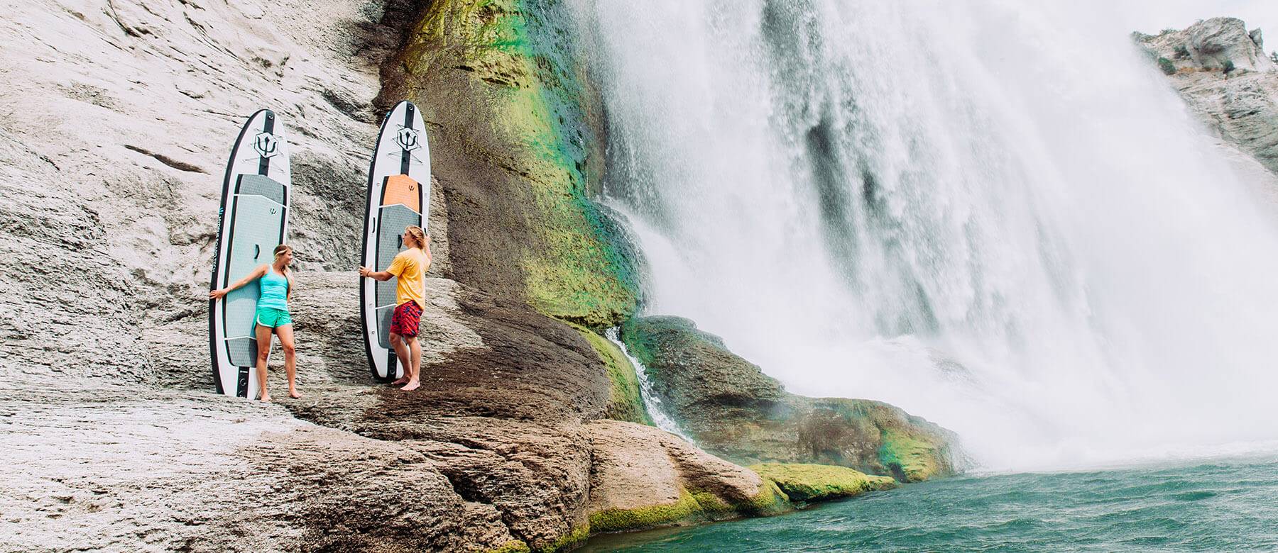 Two people stand with their paddle boards beside Shoshone Falls