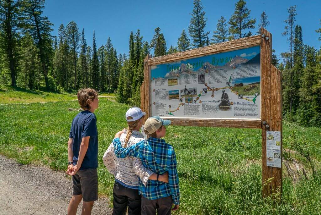 Three people standing in front of interpretive sign along the Teton Scenic Byway in Idaho.