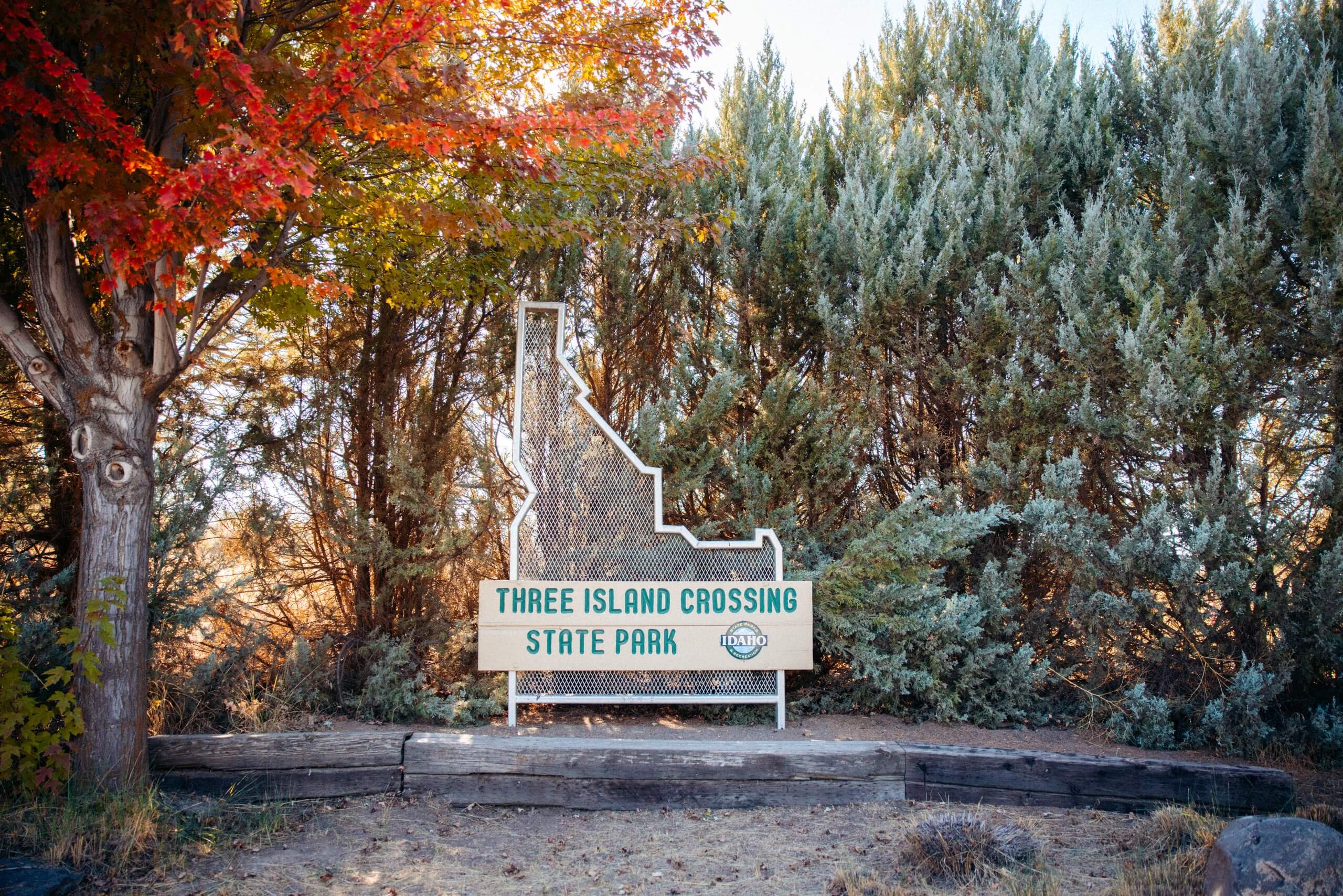 A sign shaped like the state of Idaho that reads "Three Island Crossing State Park".