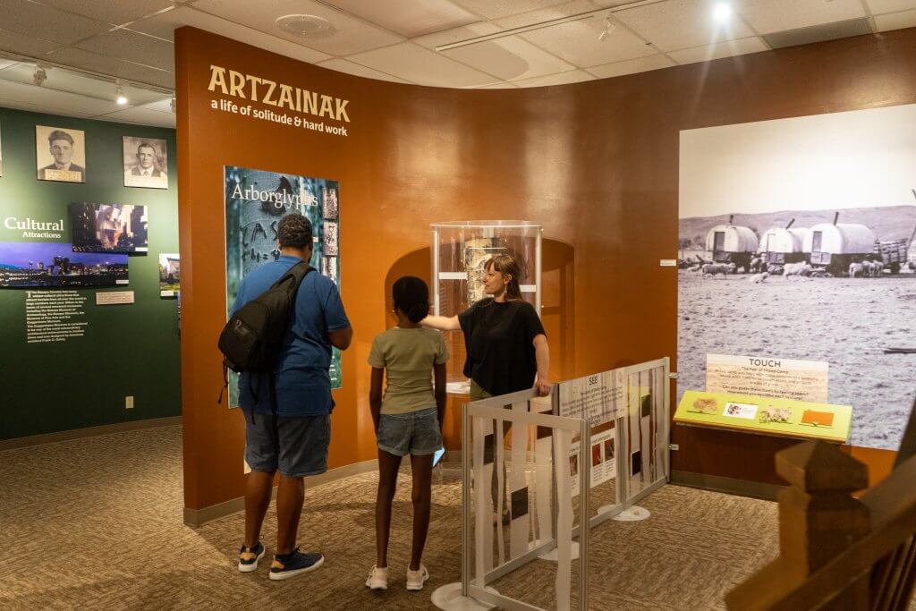 A dad and child stand side by side while listening to a staff member describe an exhibit at the Basque Museum and Cultural Center in Boise. 