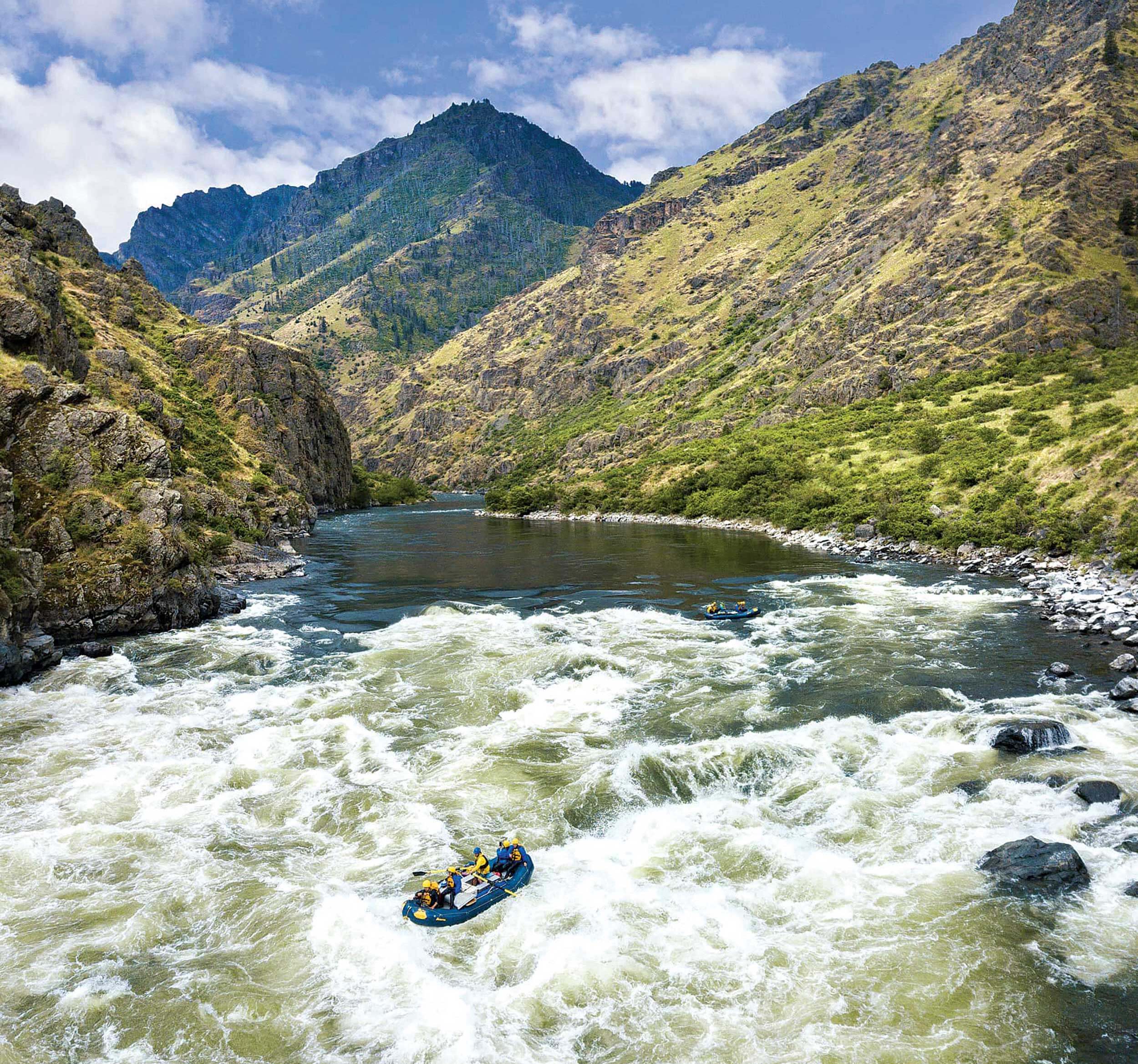 a group of people whitewater rafting on a river within a canyon